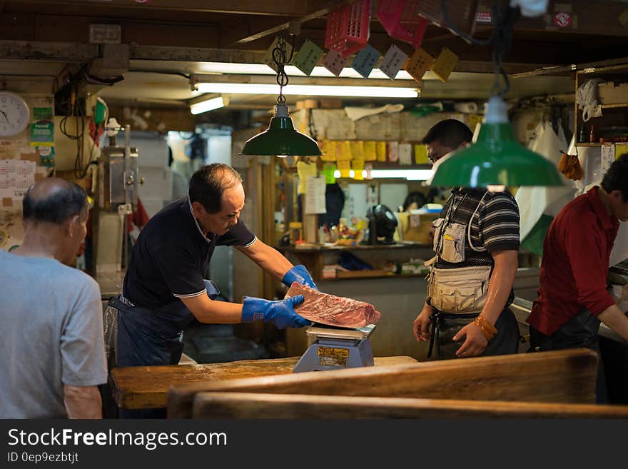 Workers cutting meat inside Asian butcher shop.