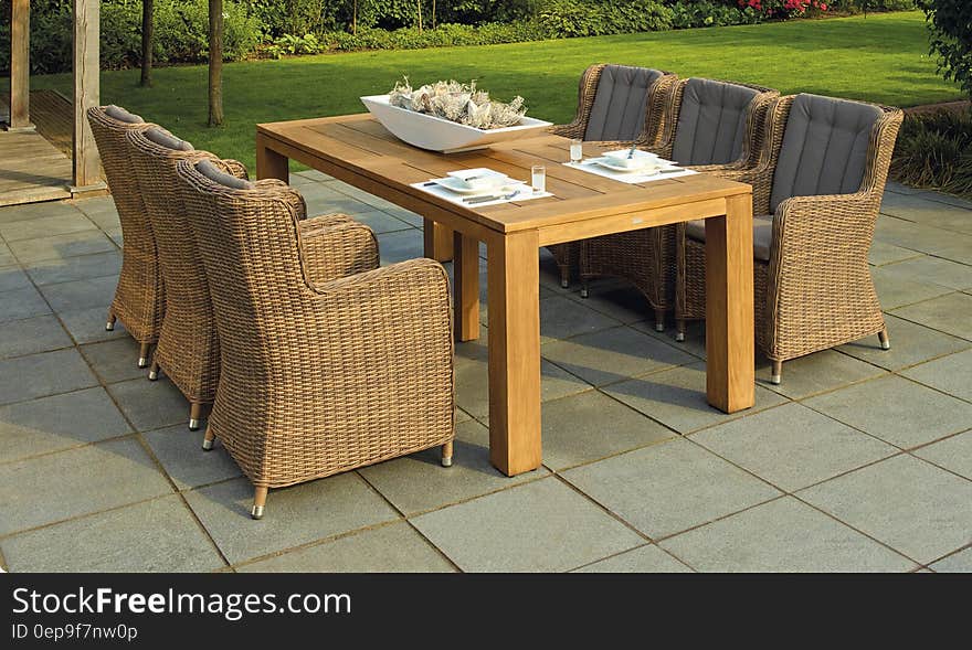 Wicker chairs and wooden patio table on garden deck on sunny day. Wicker chairs and wooden patio table on garden deck on sunny day.