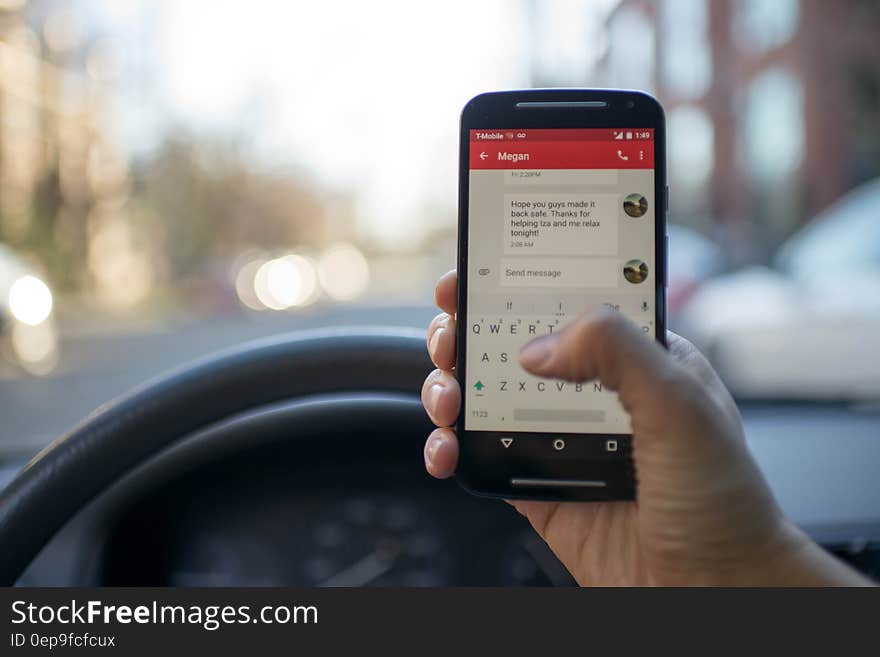 Person Sitting Inside Car With Black Android Smartphone Turned on