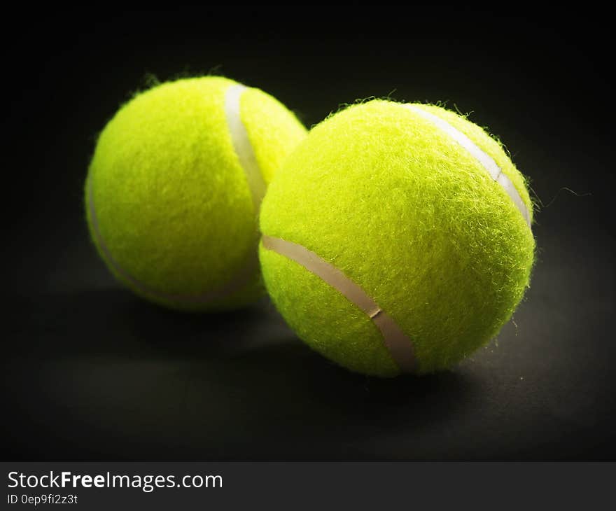 Close up of yellow tennis balls on black.