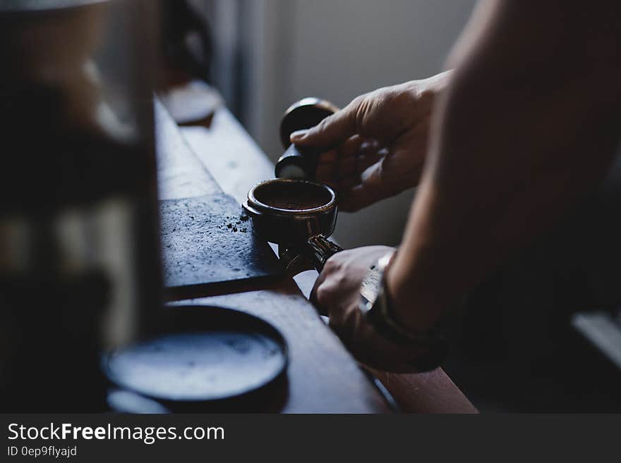 Person Holding Black Ornament While Shaping Metal Component