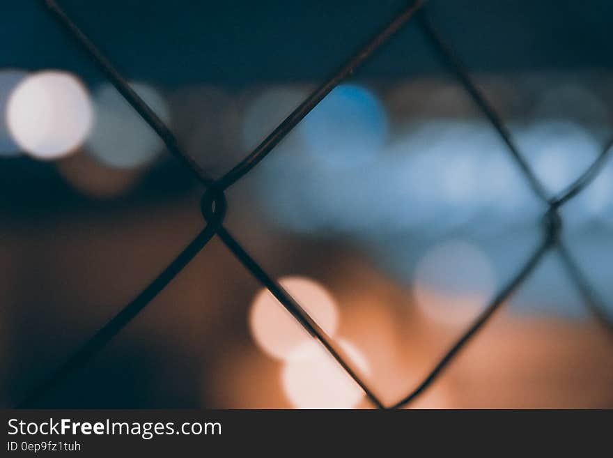 Bokeh light background against metal mesh fence at night. Bokeh light background against metal mesh fence at night.