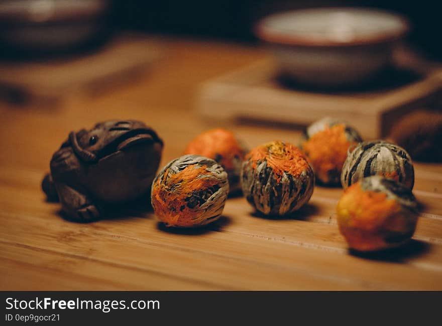 Brown Frog Figurine Beside Orange and Gray Fruits