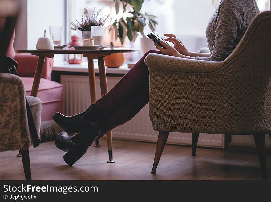 Woman Wearing Heather Gray Long Sleeve Top Red Fitted Pants and Chunky Boots Sitting on Sofa