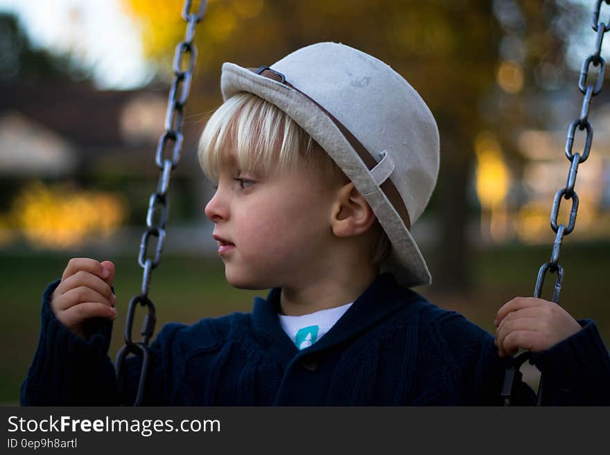 Kid in Gray Round Hat on Hanging Swing