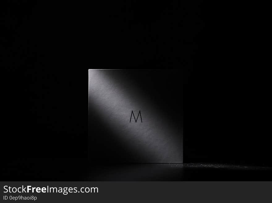 Abstract white square bathed in light with black background and copy space.