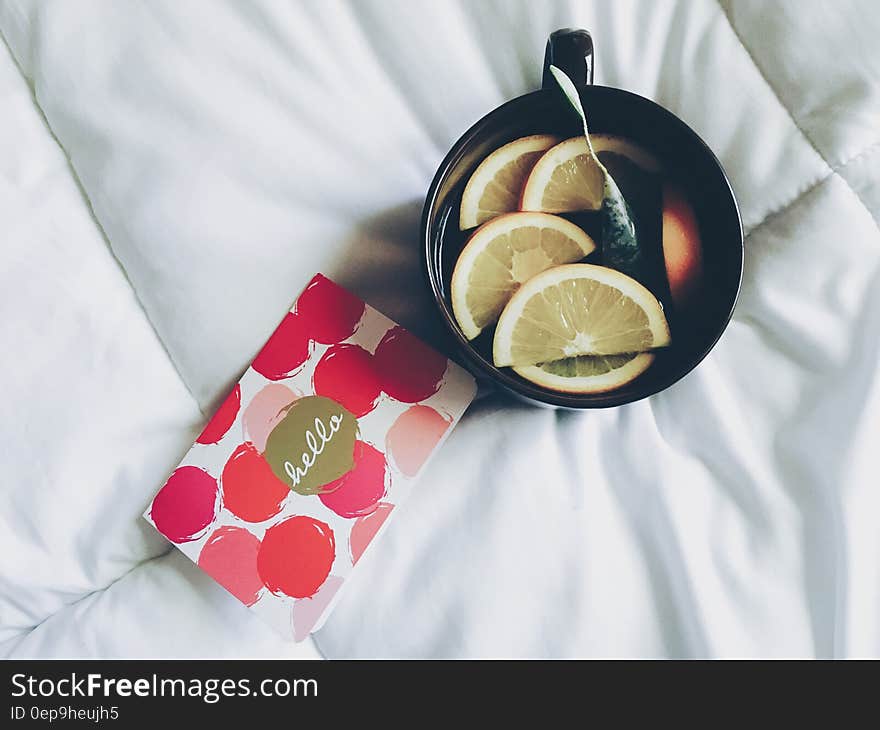 Black Ceramic Mug Filled With Sliced Orange Near Cards