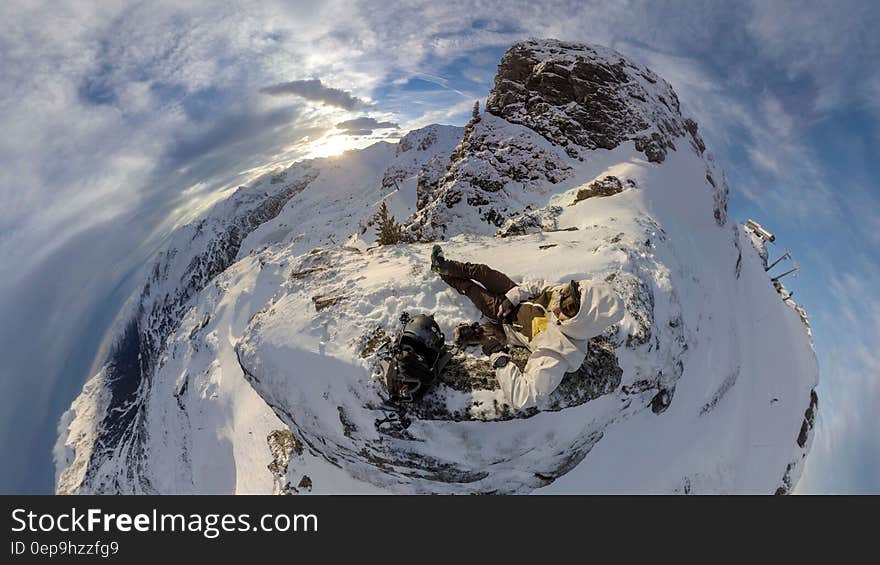 Aerial view over snow covered mountain summit with person sitting with blue skies on sunny day. Aerial view over snow covered mountain summit with person sitting with blue skies on sunny day.