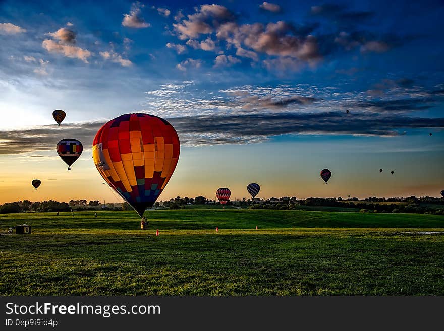 Colorful group of hot air balloons floating over countryside field at sunset with picturesque cloudscape. Colorful group of hot air balloons floating over countryside field at sunset with picturesque cloudscape.