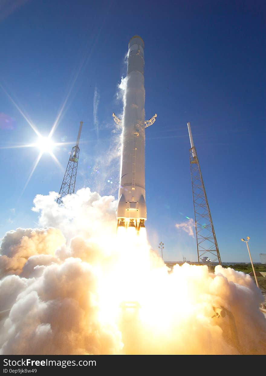 Fire and smoke from rocket launch on pad against blue skies.