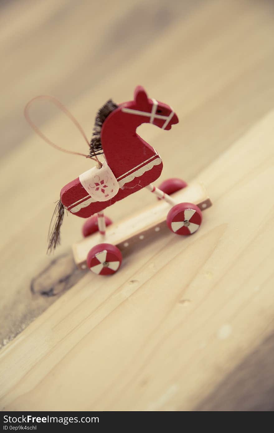 A red toy horse as a Christmas ornament on a wooden surface. A red toy horse as a Christmas ornament on a wooden surface.