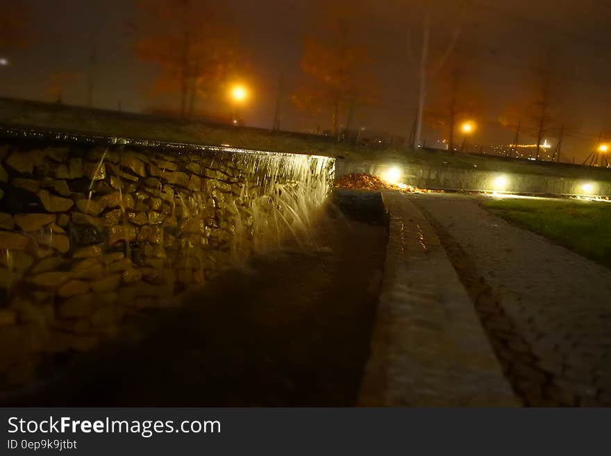 Close up of stone wall with lights along roadway at night. Close up of stone wall with lights along roadway at night.