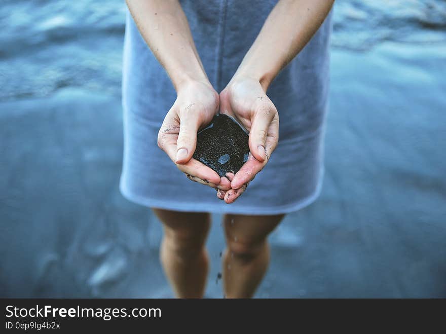 Woman standing on beach holding sand in open hands. Woman standing on beach holding sand in open hands.