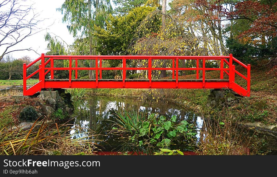 Red wooden bridge over creek in garden or park. Red wooden bridge over creek in garden or park.