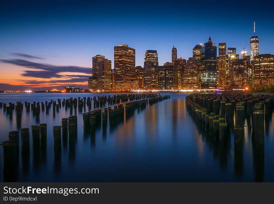 Wooden piers in waterfront alone New York City skyline illuminated at dusk. Wooden piers in waterfront alone New York City skyline illuminated at dusk.