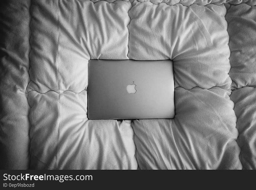 Apple Macbook laptop computer on bedspread in black and white.