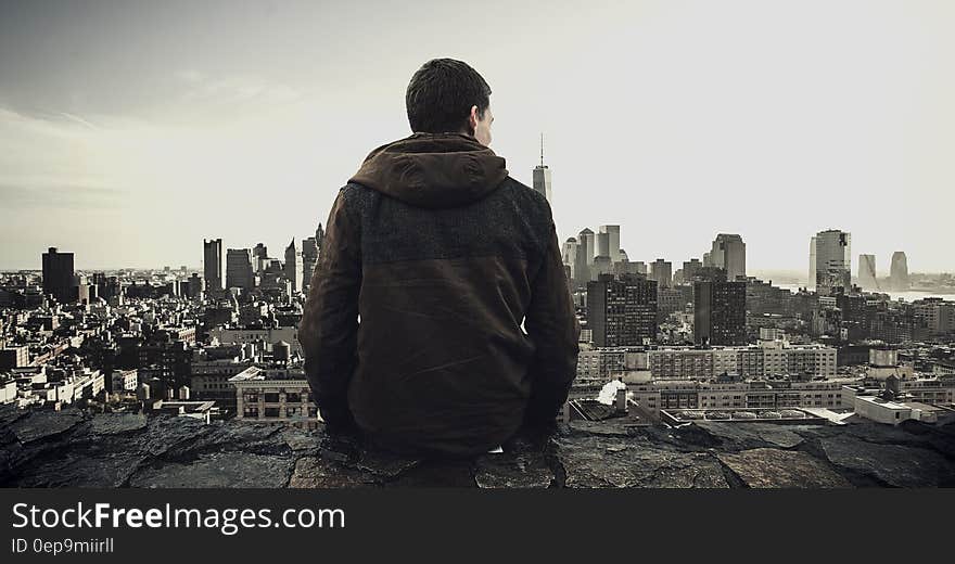 Man standing on rooftop overlooking urban skyline and waterfront. Man standing on rooftop overlooking urban skyline and waterfront.