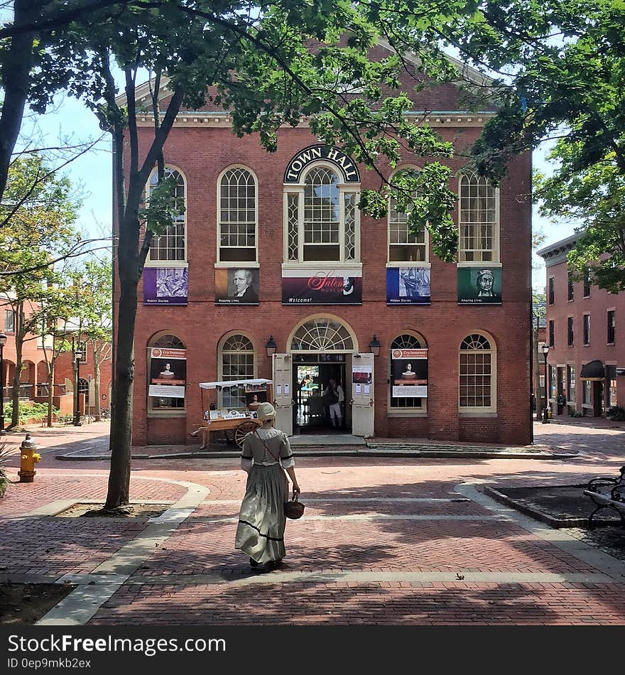 Woman in Colonial dress walking along pathway outside historic Town Hall. Woman in Colonial dress walking along pathway outside historic Town Hall.