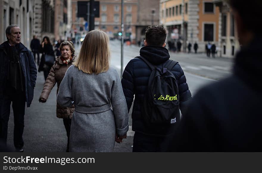 Couple Holding Hands While Walking on the Street