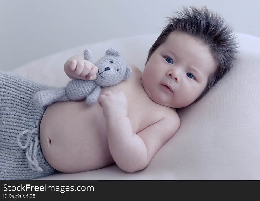 Studio portrait of Asian infant boy holding knit teddy bear. Studio portrait of Asian infant boy holding knit teddy bear.