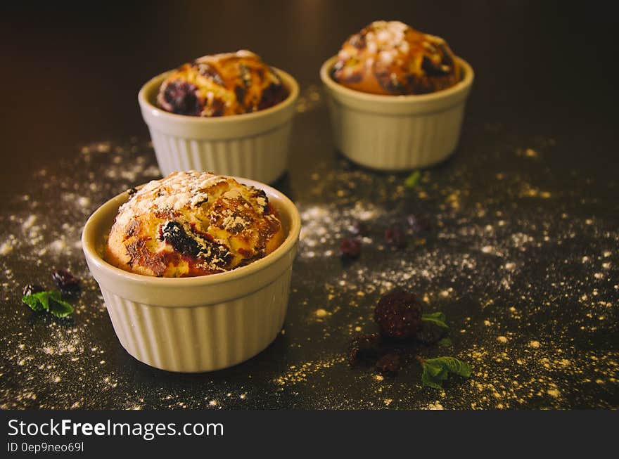 Close up of blueberry muffins backed in white china ramekins sprinkled with powdered sugar. Close up of blueberry muffins backed in white china ramekins sprinkled with powdered sugar.