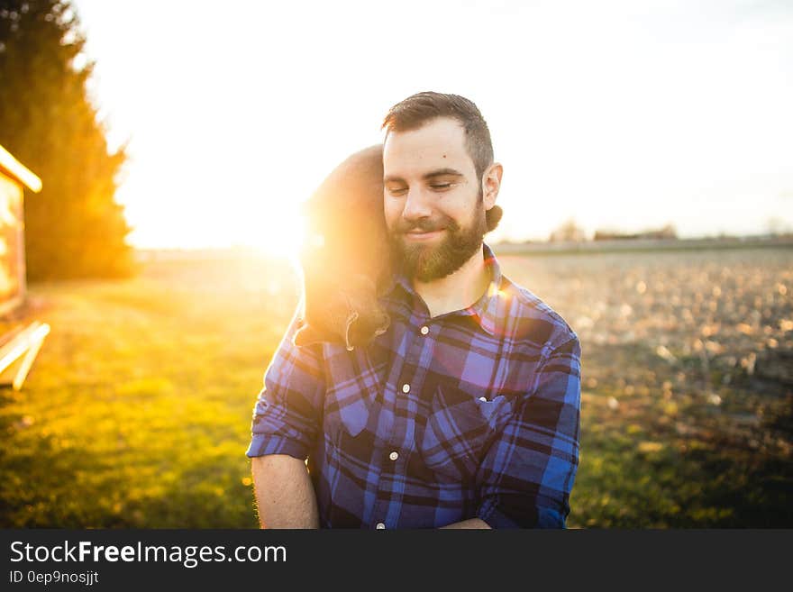 A man standing beside a green field with a cat on his shoulder. A man standing beside a green field with a cat on his shoulder.