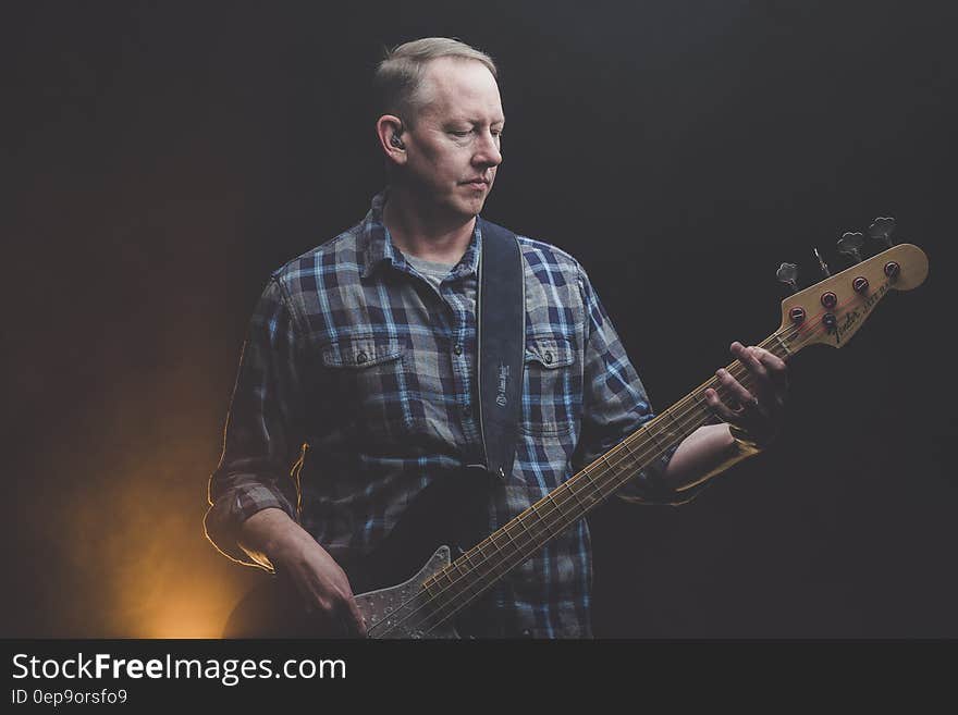 A man with a bass guitar on a stage. A man with a bass guitar on a stage.