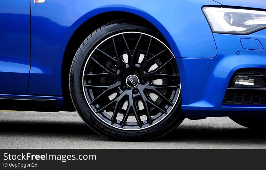 Close up of tire and front section of blue Audi luxury car. Close up of tire and front section of blue Audi luxury car.