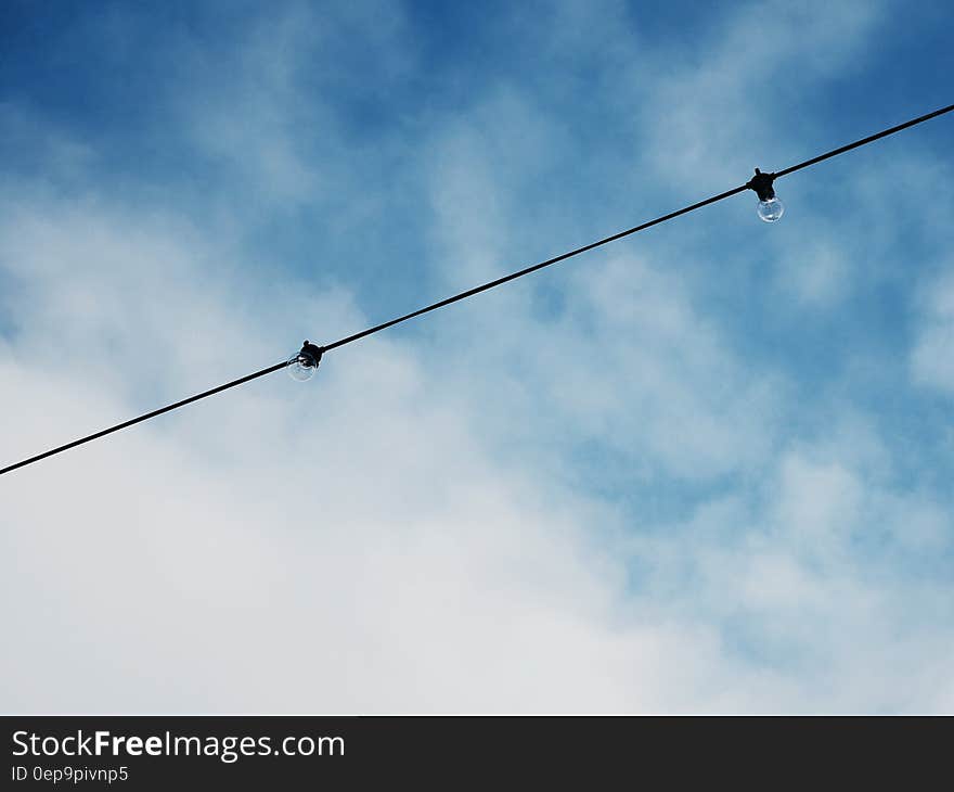 Electric Cable With Light Bulb Under Bright Sky