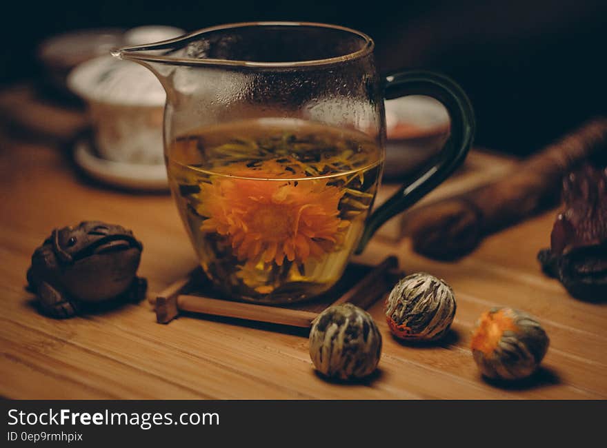 Orange Petaled Flowers in Clear Glass Pitcher With Water on Brown Table Close Up Photography