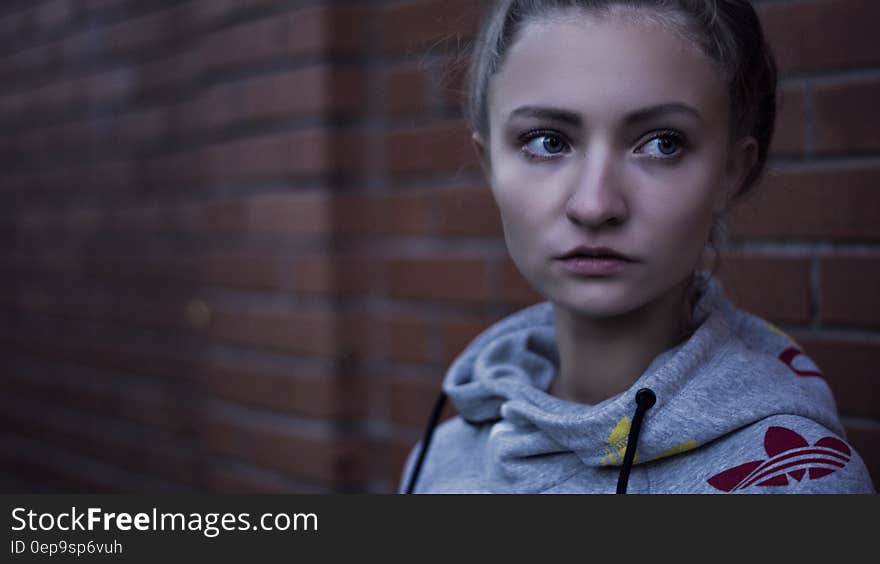 Macro Shot of Woman in Gray Adidas Pull over Hoodie Near Brick Wall