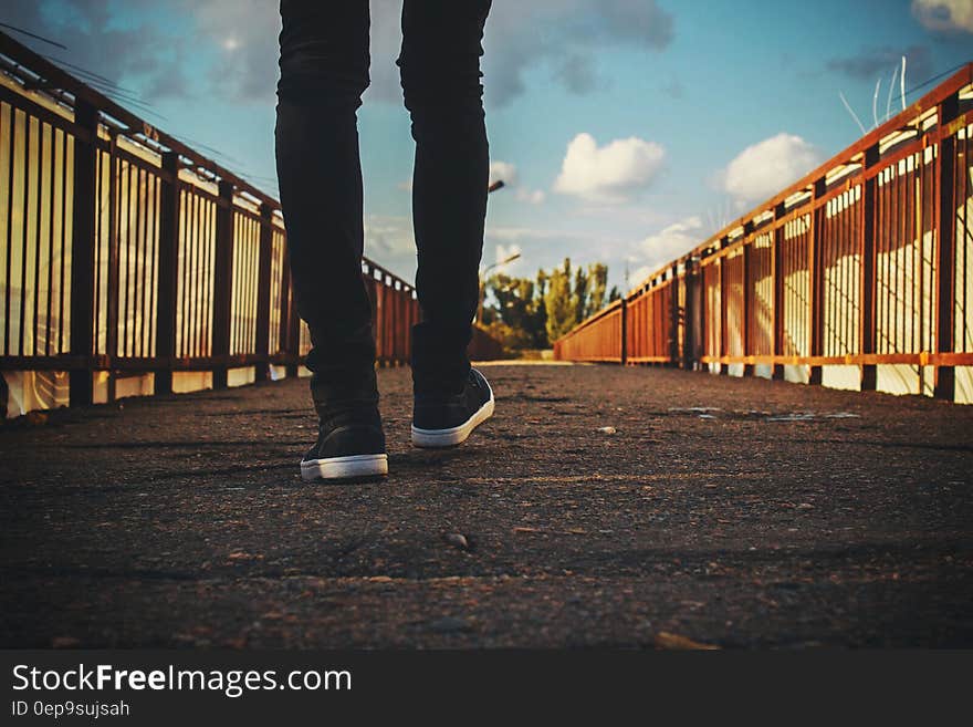 Feet wearing sneakers walking across bridge on sunny day. Feet wearing sneakers walking across bridge on sunny day.