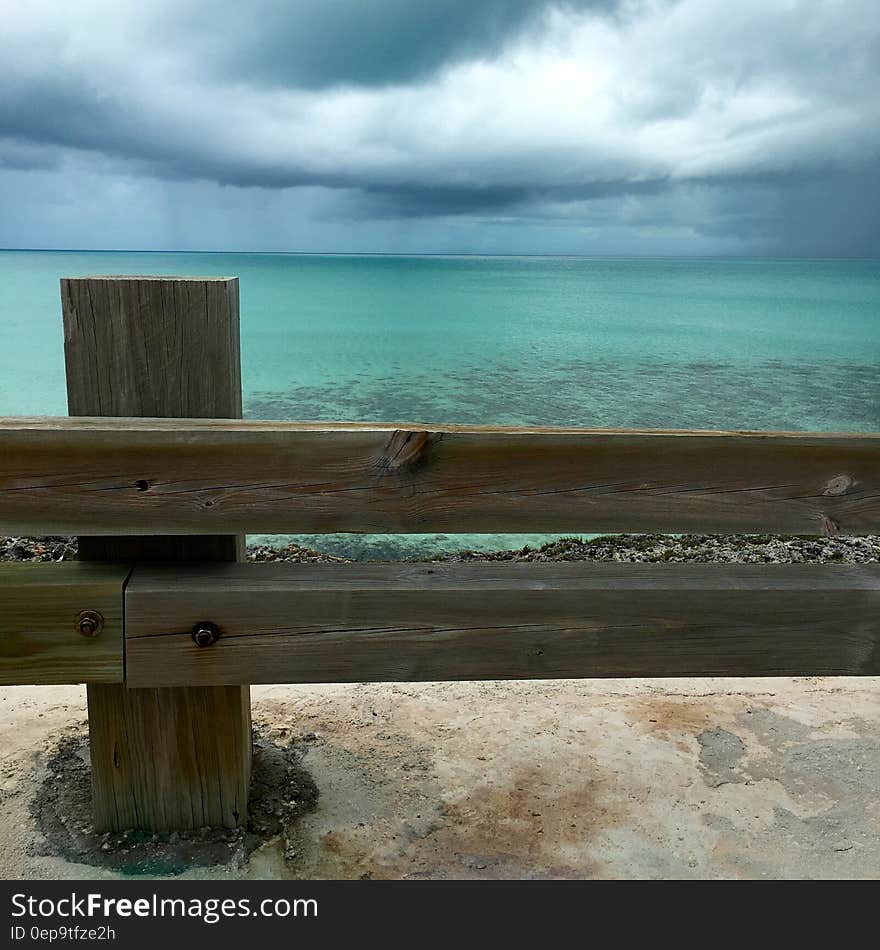 Brown Wooden Fence Near Blue Ocean Water Under White Cloudy Sky during Daytime