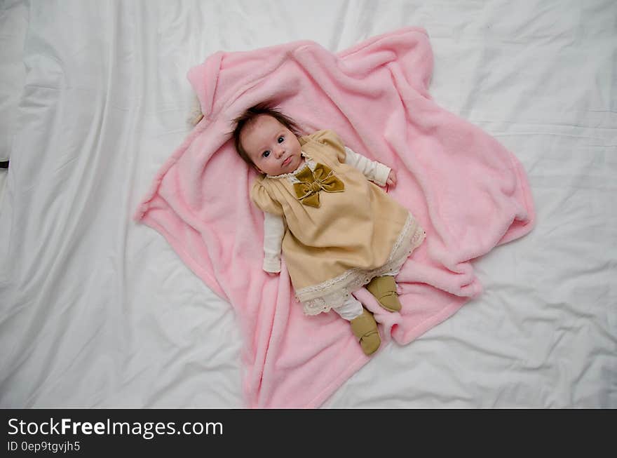 Baby in White and Yellow Dress on Pink Textile