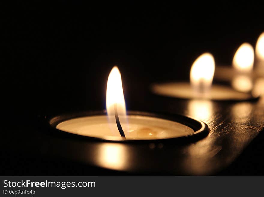 Lit tea candles isolated on black.