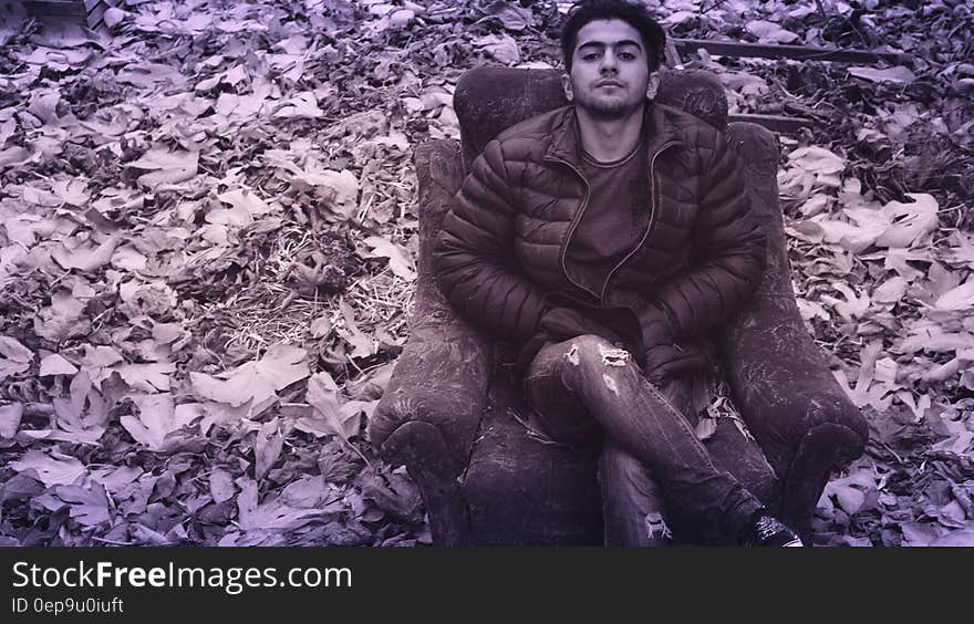 Man in Black Puffer Jacket and Distress Jeans Sitting in Couch