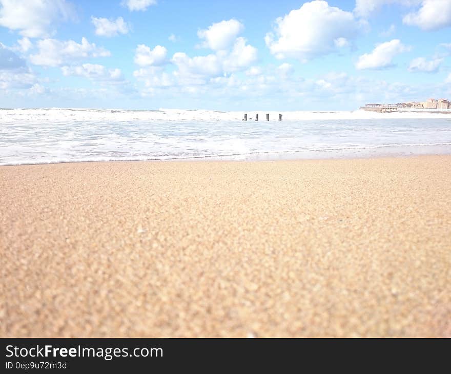 Large sandy beach, tranquil sea or ocean with breakwaters and blue sky and cloud all in pastel shades of color. Large sandy beach, tranquil sea or ocean with breakwaters and blue sky and cloud all in pastel shades of color.