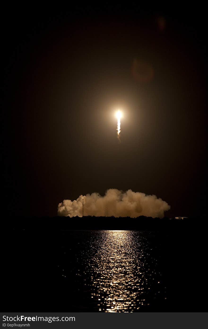 Rocket blast off reflected in water at night with plume of smoke and steam. Rocket blast off reflected in water at night with plume of smoke and steam.