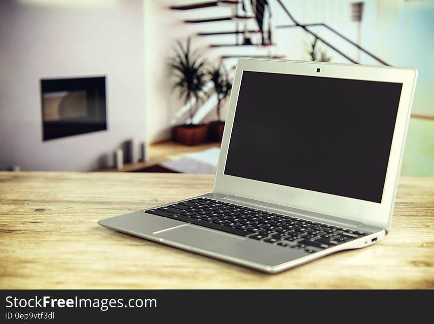 Laptop computer open on wooden table inside home. Laptop computer open on wooden table inside home.