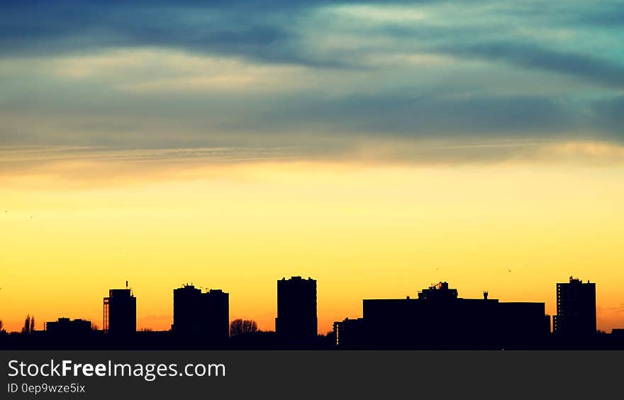 Silhouette of urban skyline against orange and blue skies at sunset. Silhouette of urban skyline against orange and blue skies at sunset.