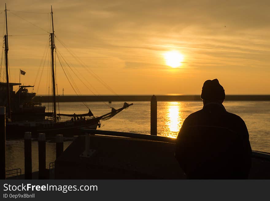 Person Standing on Dock during Sunset