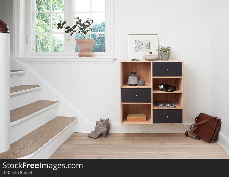 Stairway with boots and briefcase next to shelves inside modern home on sunny day. Stairway with boots and briefcase next to shelves inside modern home on sunny day.