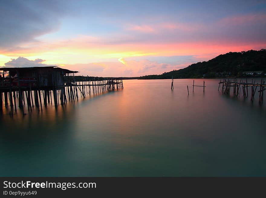 Wooden pier on coastline at sunset with pink skies. Wooden pier on coastline at sunset with pink skies.