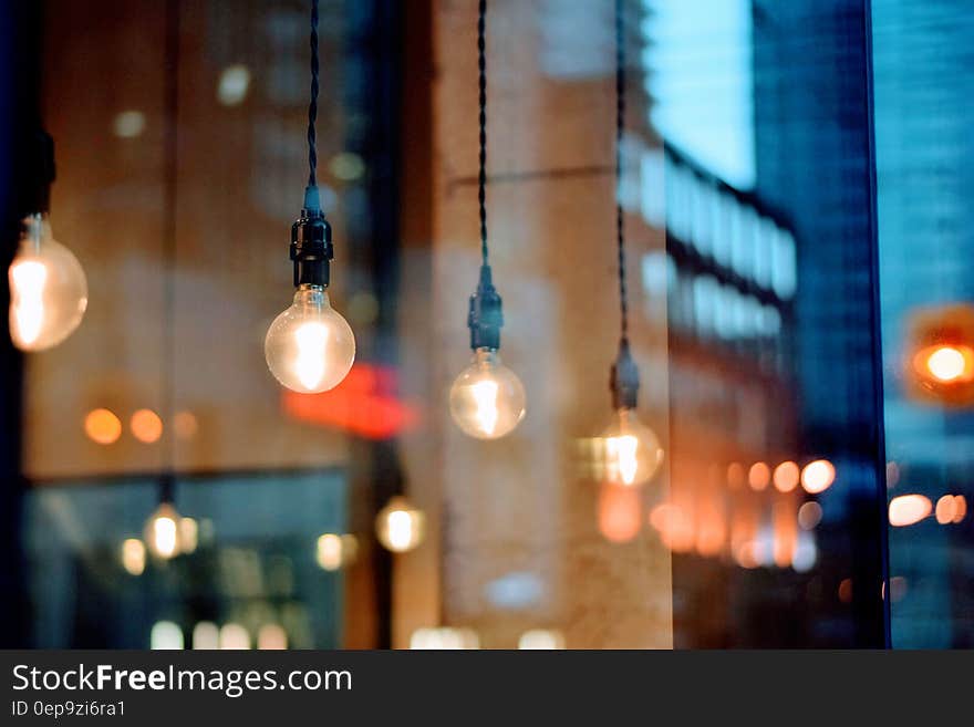 Light fixtures illuminated inside modern cafe with reflection of urban skyline. Light fixtures illuminated inside modern cafe with reflection of urban skyline.