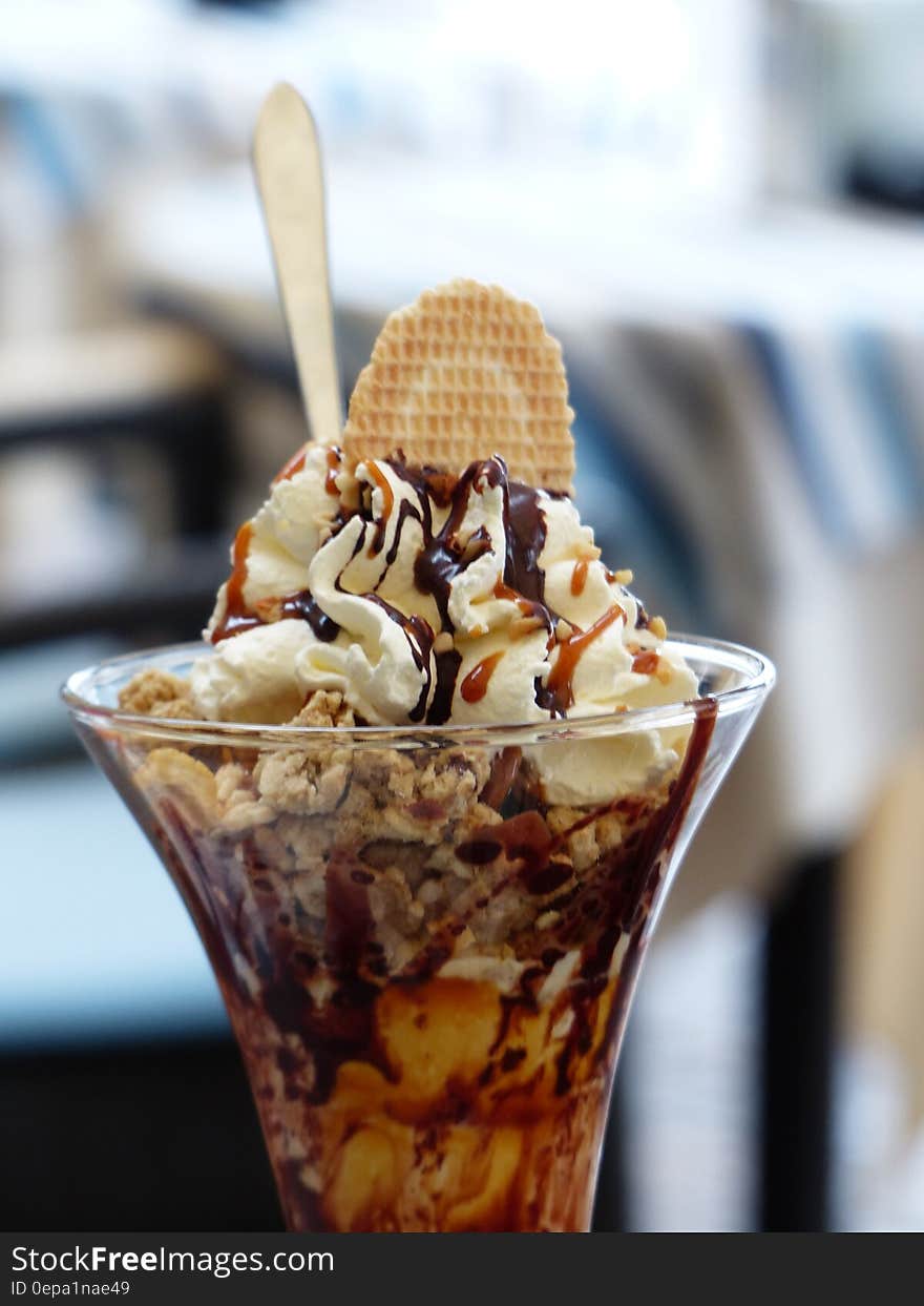 Chocolate ice cream sundae in glass with spoon and wafer.