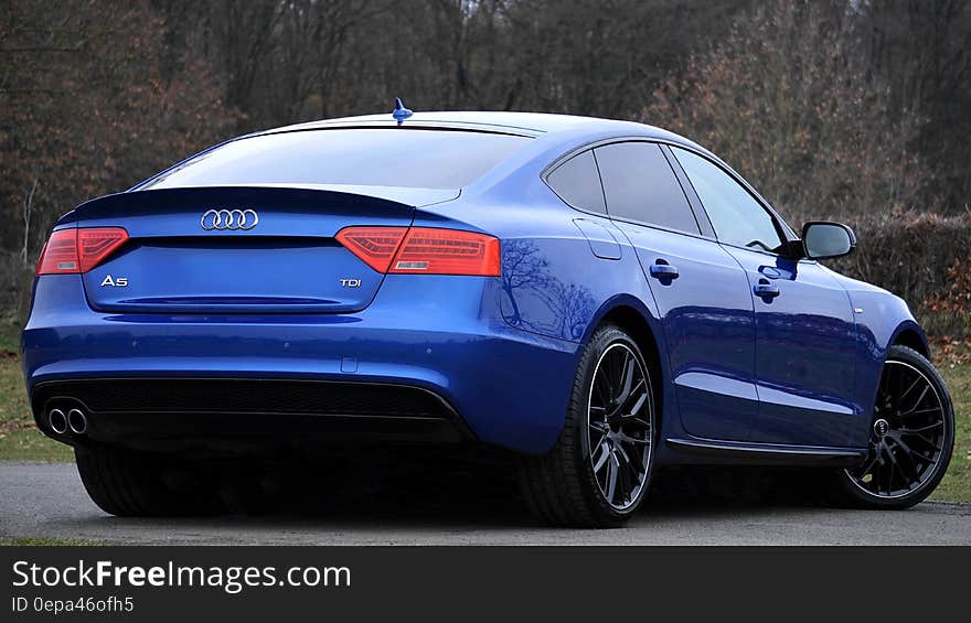 Blue Audi sports coupe on roadway from behind. Blue Audi sports coupe on roadway from behind.