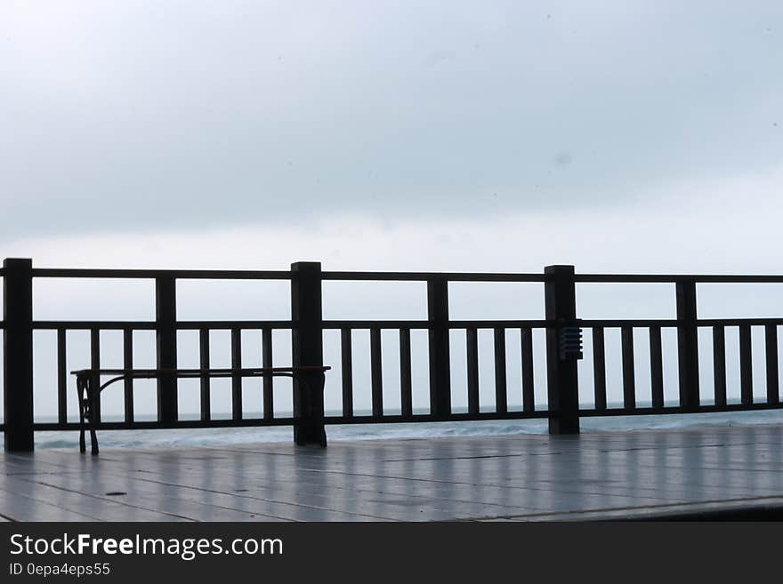 Wooden waterfront dock or boardwalk with railing against cloudy skies. Wooden waterfront dock or boardwalk with railing against cloudy skies.