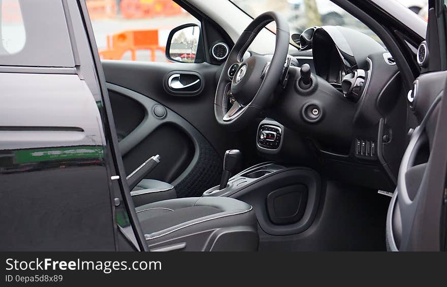 Black leather steering wheel and dash in interior of luxury car outdoors. Black leather steering wheel and dash in interior of luxury car outdoors.