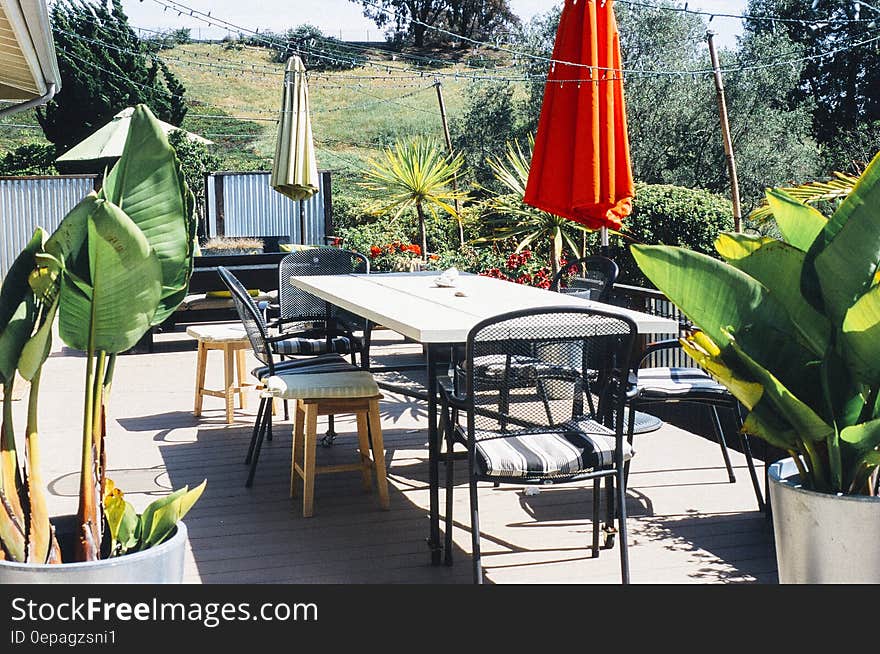 Patio table and chairs with closed umbrella on sunny deck. Patio table and chairs with closed umbrella on sunny deck.