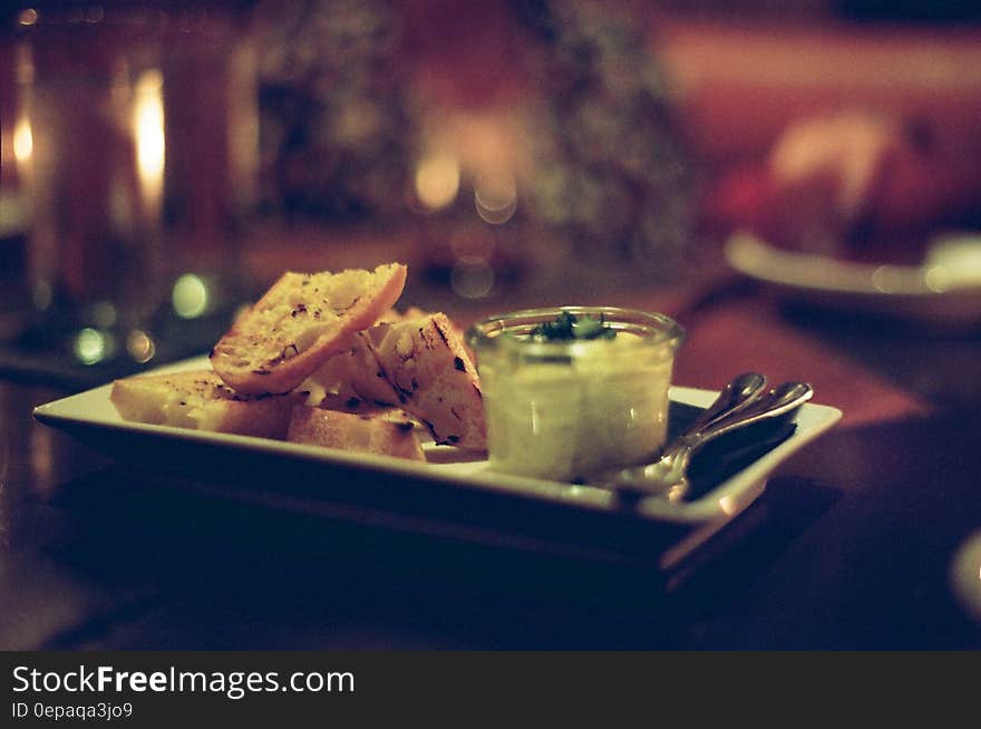 Restaurant tabletop with white china plate of toasted bread and dip appetizer. Restaurant tabletop with white china plate of toasted bread and dip appetizer.